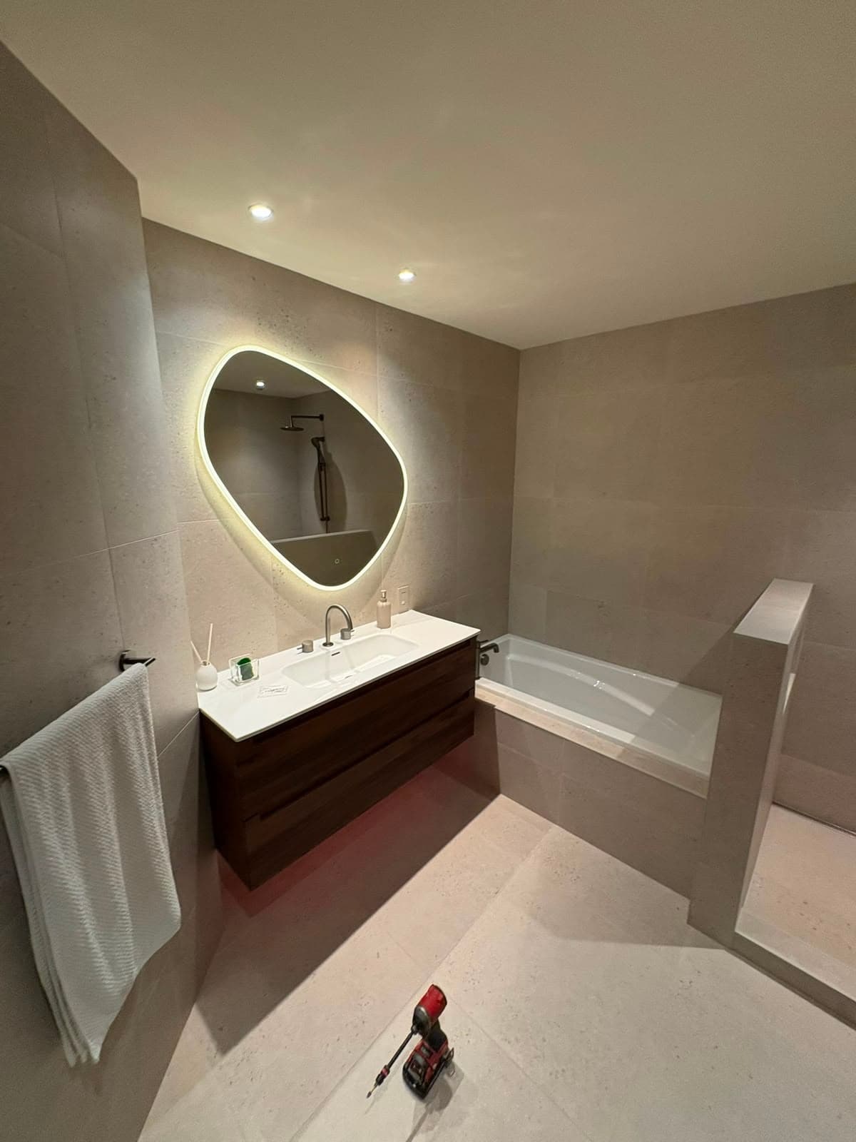 Salle de bain avec vanité flottante en bois foncé et miroir rétroéclairé